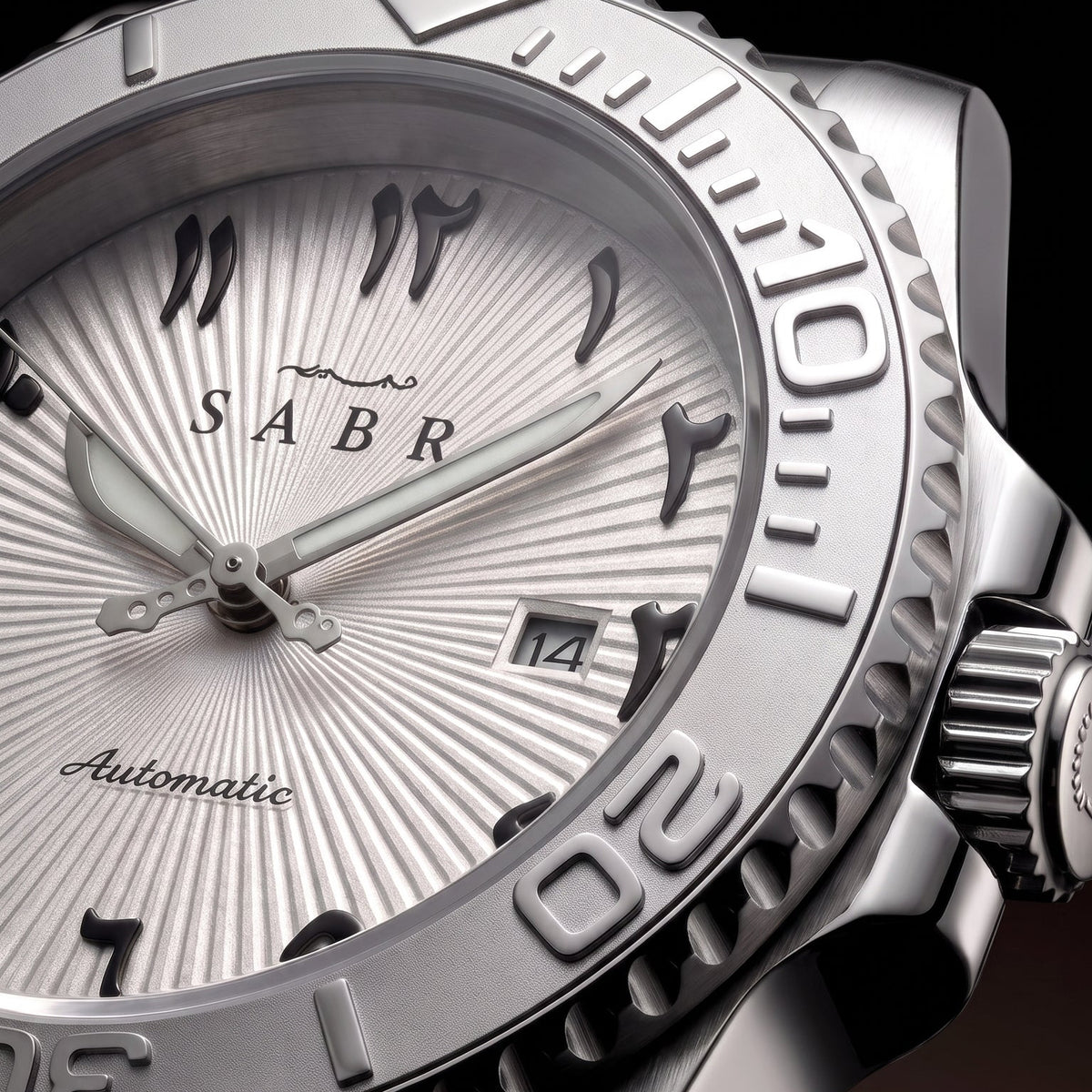 Sabr automatic watch with a silver sunburst dial, black Arabic numeral hour markers, a textured stainless steel bezel, and a matching metal bracelet, shown against a dark background.